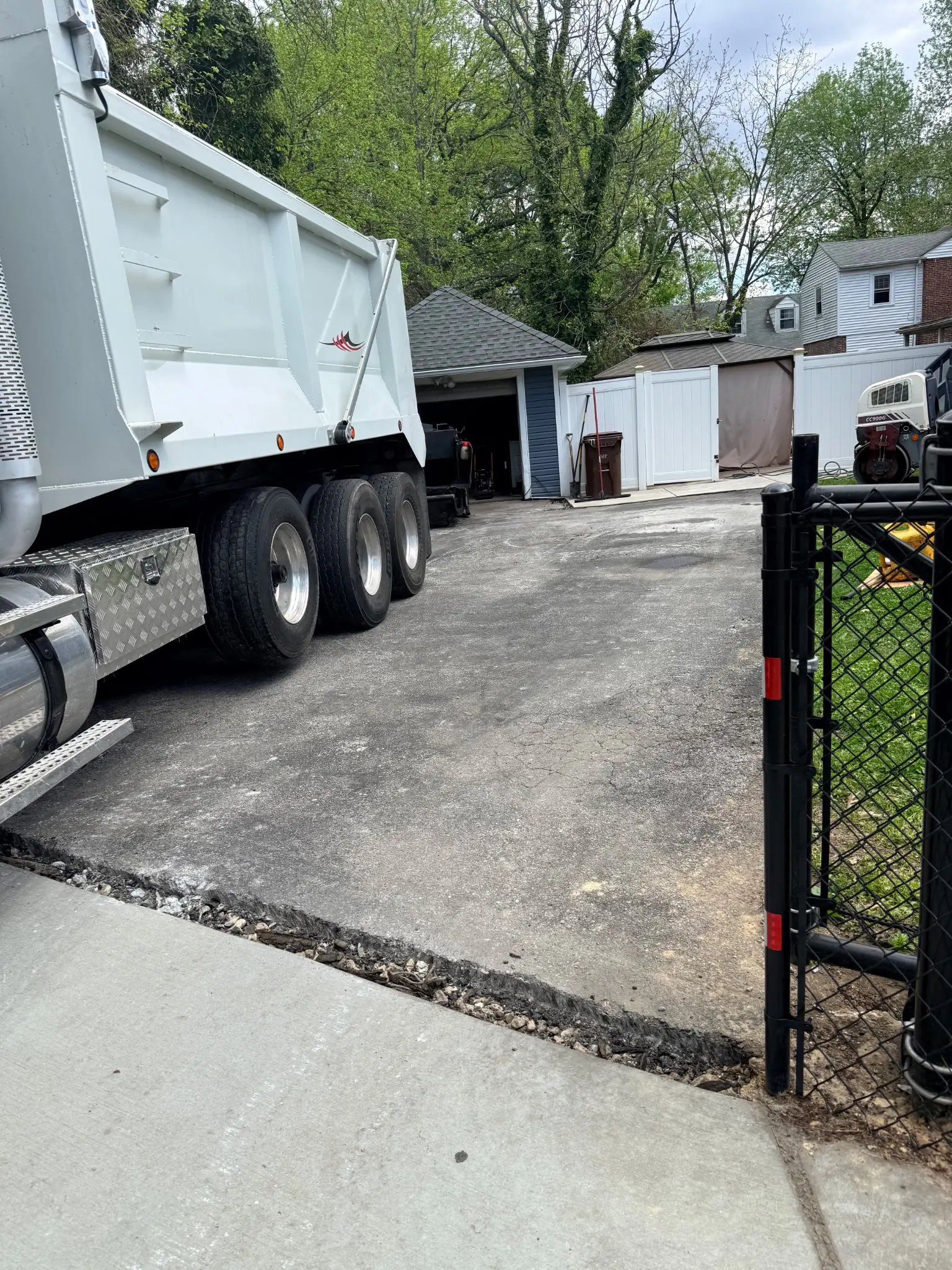 Dump truck staged on a residential driveway during asphalt tear-out and prep work